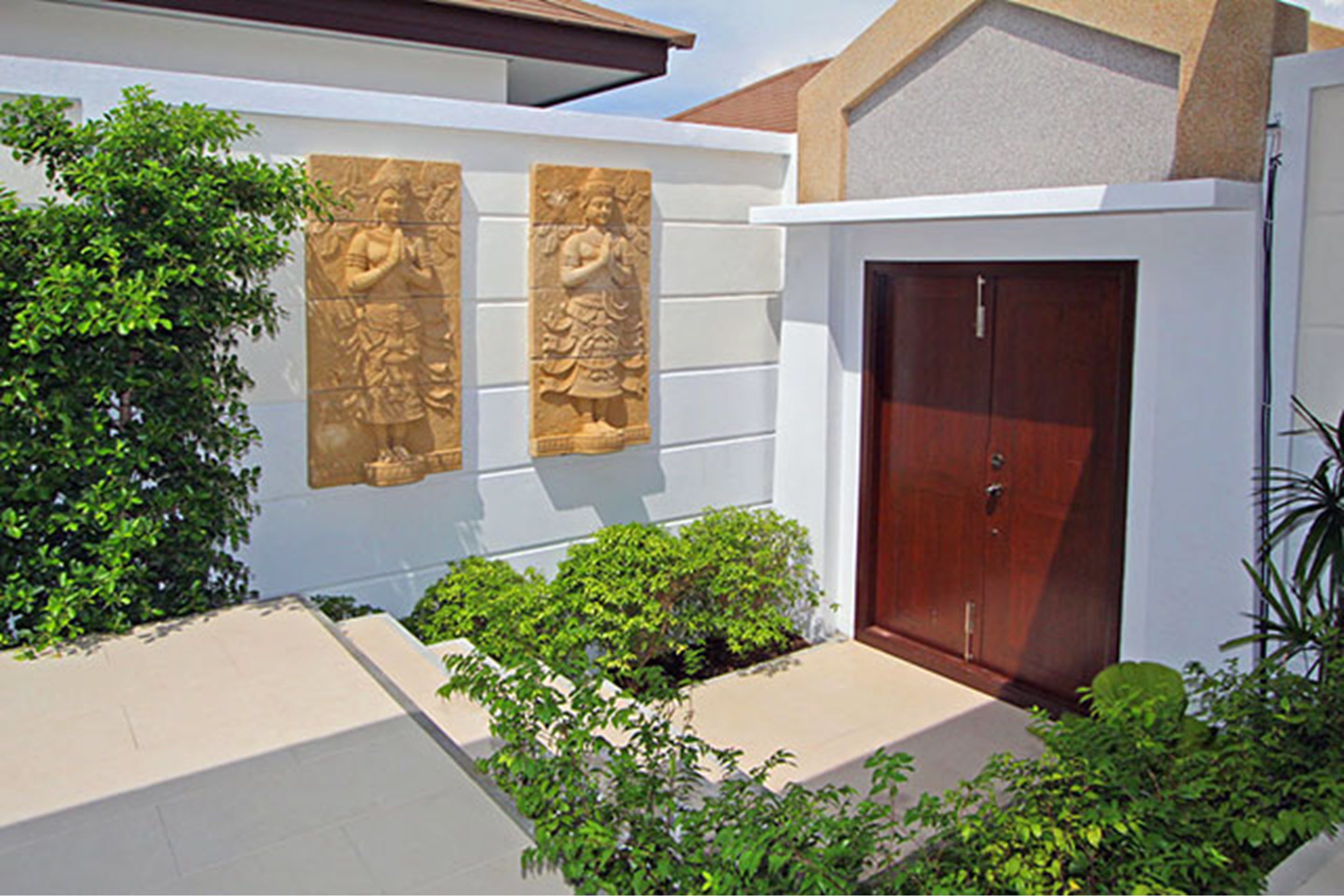 A building with a white exterior, a wooden door, and two stone carvings on the wall.