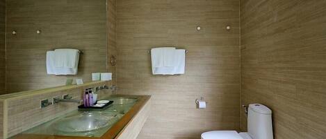 Un baño moderno con un lavabo de vidrio, un inodoro y paredes de madera.