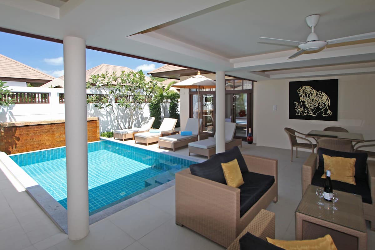 A modern outdoor living area with a pool, lounge chairs, and a dining table.