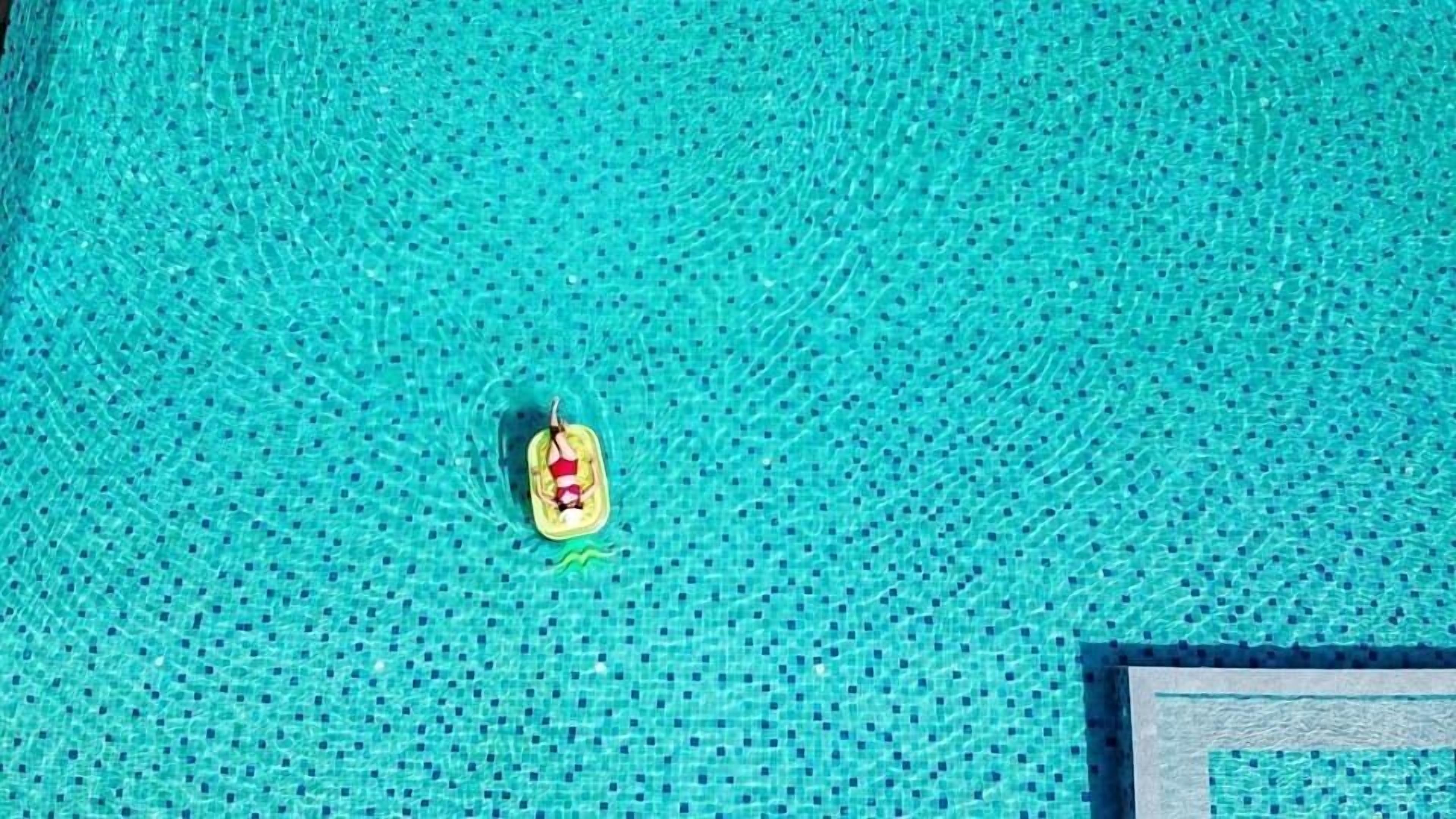 A pool with a small yellow float and a person lying on it.