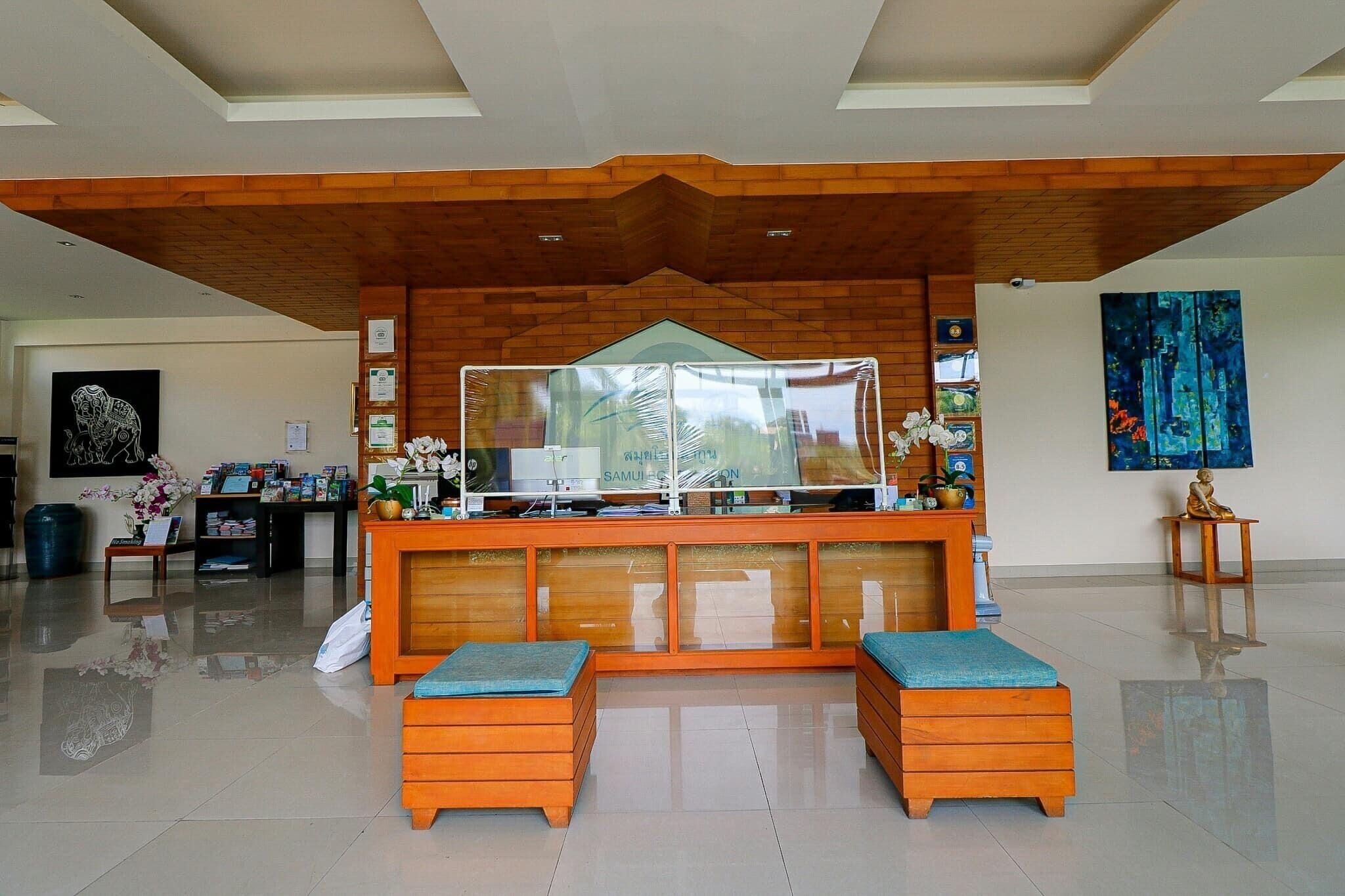 A reception area with a wooden counter, two cushioned seating areas, a glass display case, and artwork on the walls.