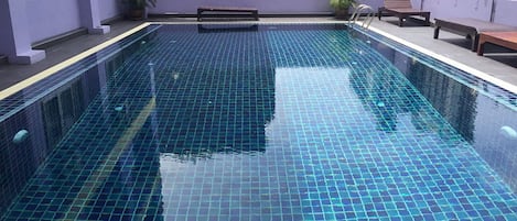 Alberca al aire libre, sombrillas en la alberca y camastros