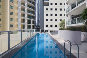 Una piscina al aire libre, sillones reclinables de piscina