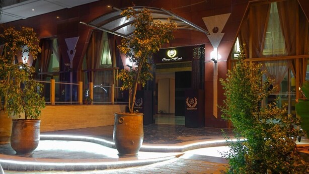 L'entrée d'un hôtel au design moderne, agrémentée de grands pots de plantes et d'un espace d'entrée bien éclairé.