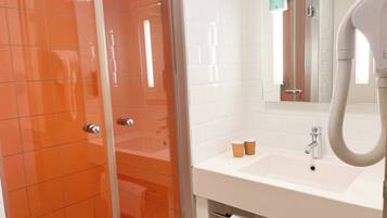 A bathroom with a shower, a sink, and a mirror.