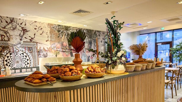 Un mostrador de buffet con diferentes alimentos, un florero decorativo y un mural en la pared.