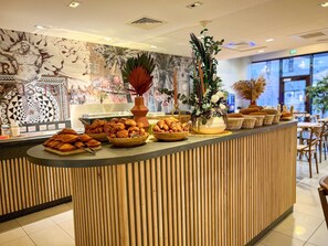 Un mostrador de buffet con diferentes alimentos, un florero decorativo y un mural en la pared.