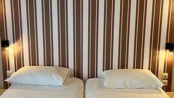A hotel room with two beds, a striped wall, and wall-mounted light fixtures.