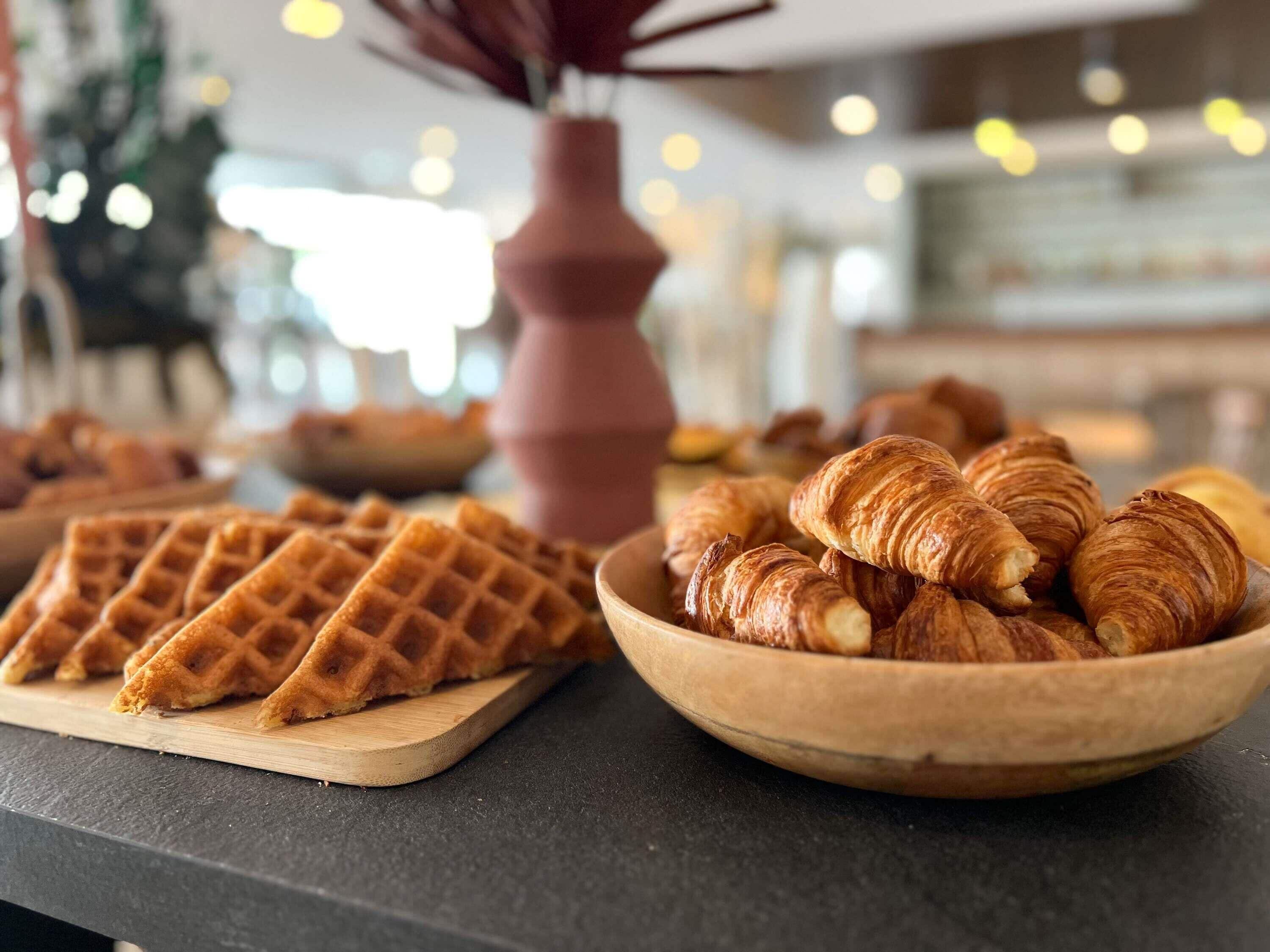 A breakfast buffet with waffles and croissants.