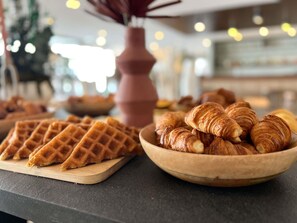 Un bufé de desayuno con gofres y cruasanes.