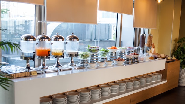 Un buffet proposant différents stands de nourriture, notamment des fruits, des salades et des boissons.