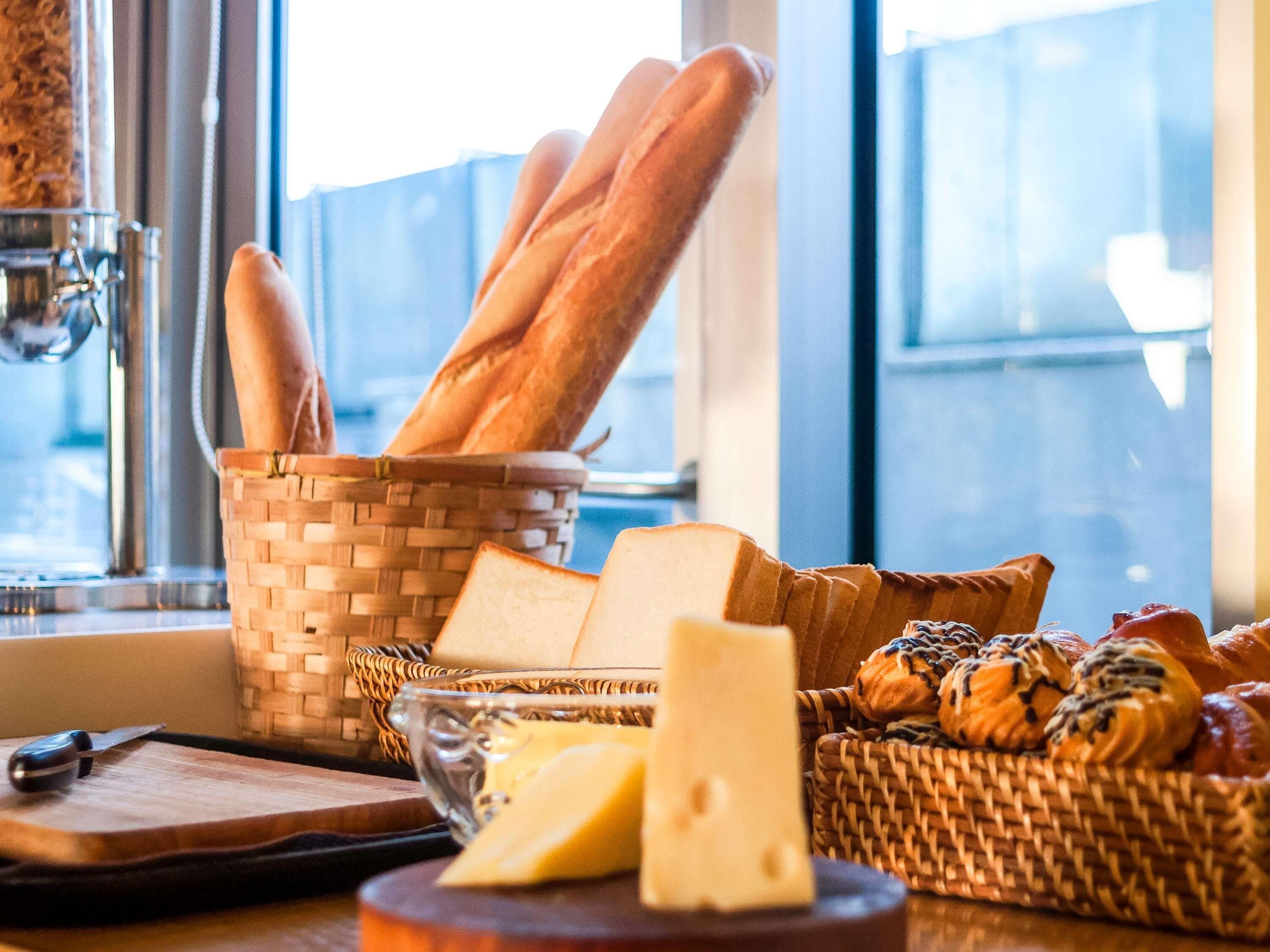Una encimera de cocina con pan, queso y una cesta de pasteles.