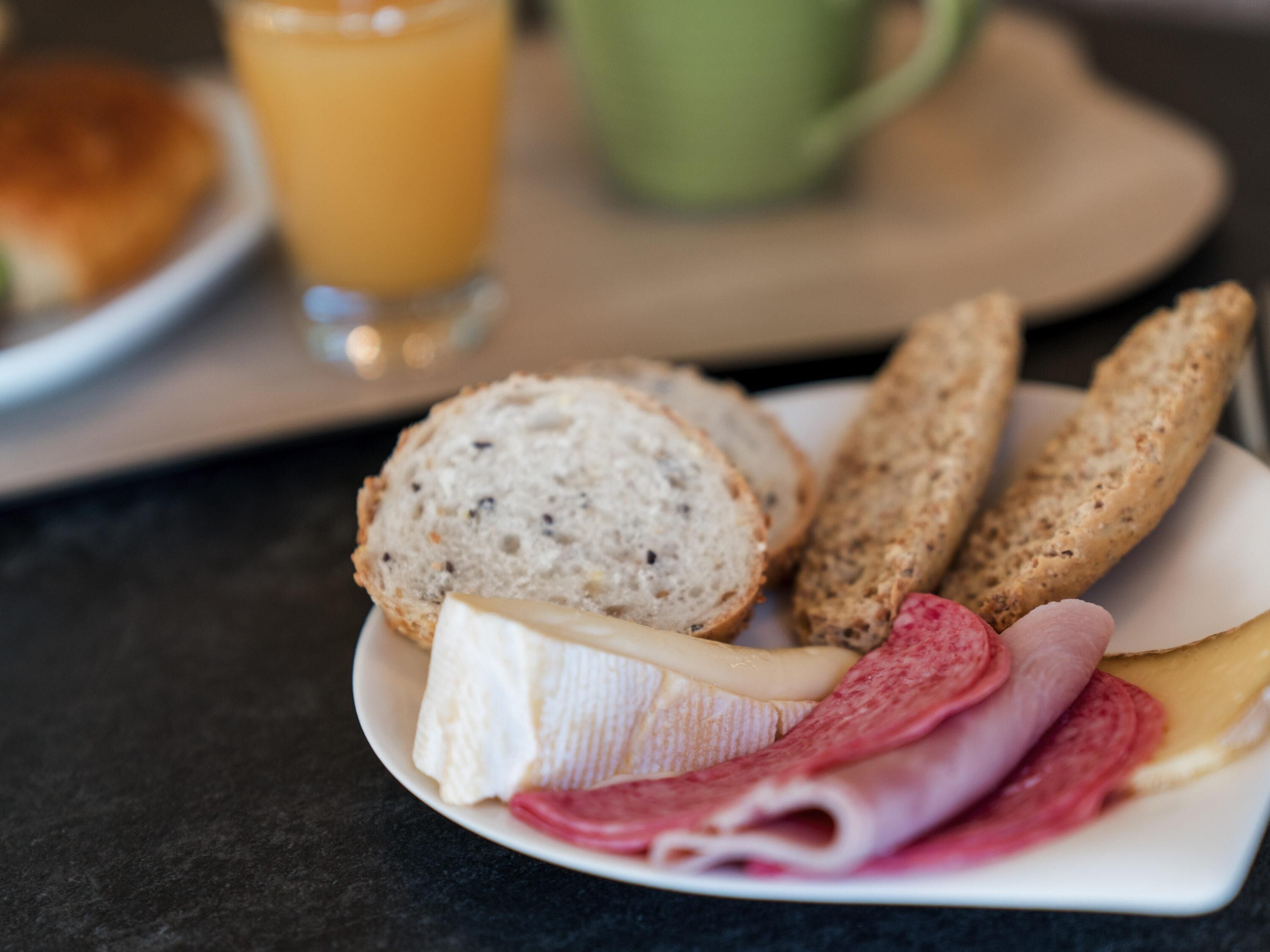 Une assiette de petit-déjeuner avec du pain, du fromage et du jambon.