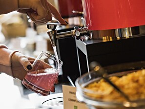 Una persona sirviendo una bebida desde una máquina de café en un vaso.