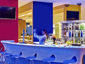 Un espace bar avec des tabourets, un comptoir et une étagère remplie de bouteilles.