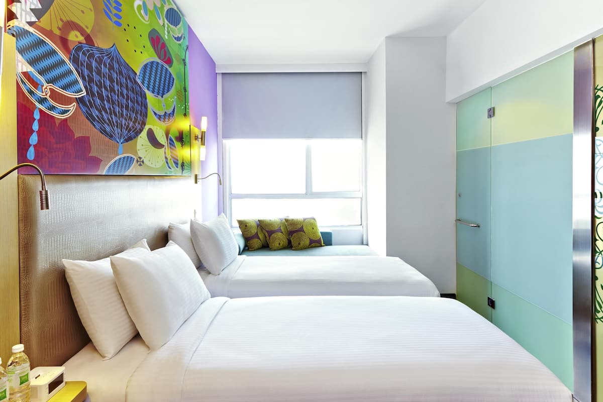 Habitación de hotel con dos camas, un mural colorido, una ventana y un armario.
