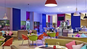 Un restaurante moderno con colores vibrantes, mesas redondas y sillas naranjas.