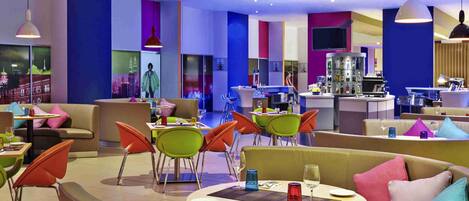 Un restaurante moderno con colores vibrantes, mesas redondas y sillas naranjas.