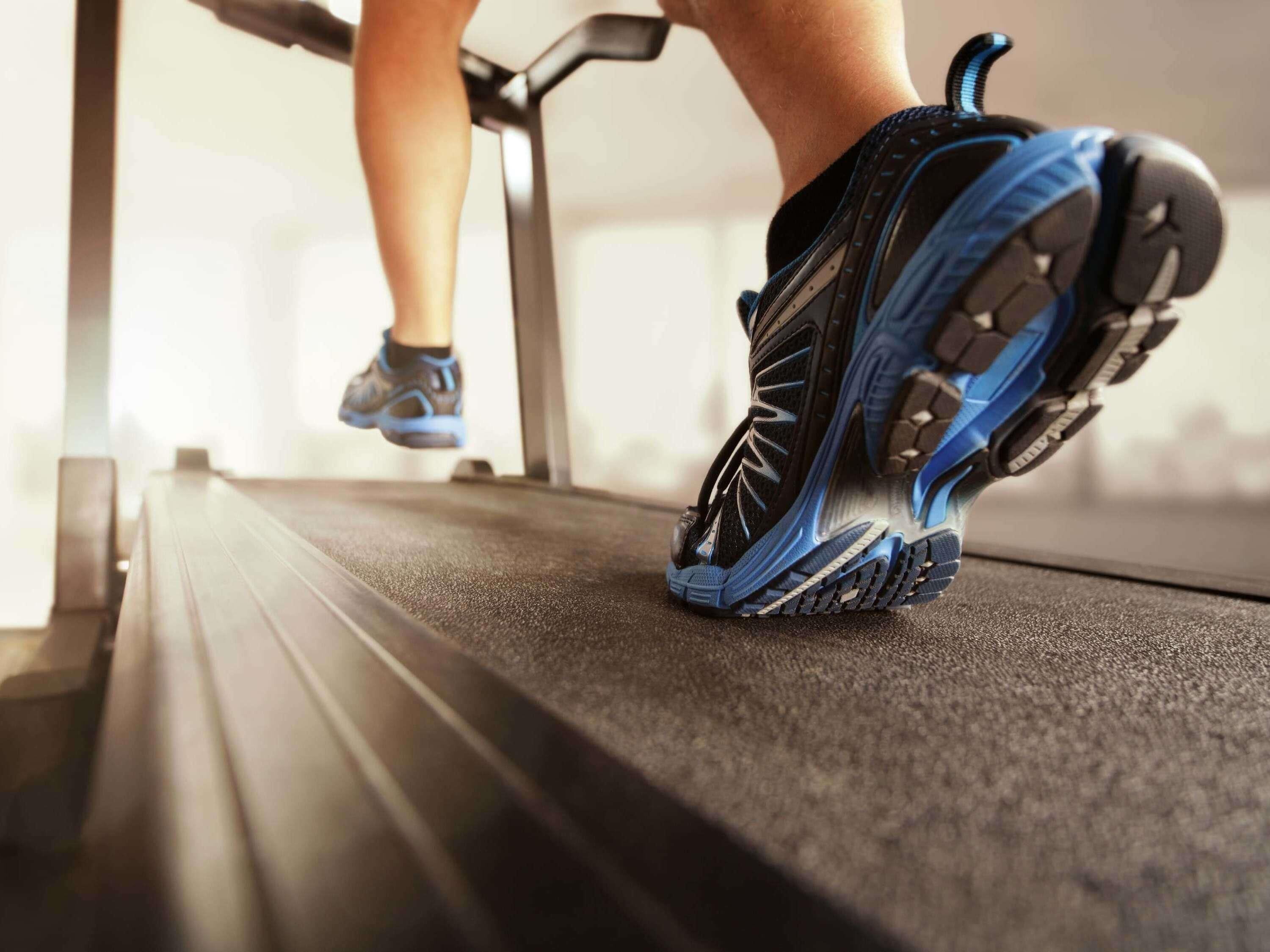 A close-up of a person's running shoe on a treadmill.