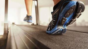 A close-up of a person's running shoe on a treadmill.