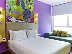 Habitación de hotel con una cama grande, un sofá, un mural de pared colorido y una ventana.