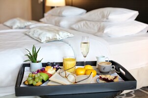 Una bandeja de desayuno ordenada sobre una cama, con una bebida, fruta y un libro.