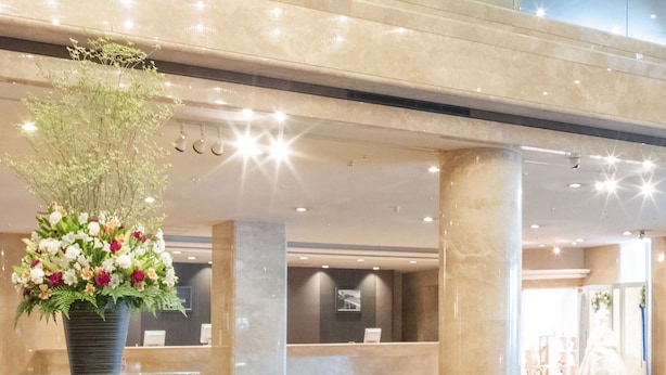 A spacious lobby with a reception desk, a large floral arrangement, and a modern architectural design. - Hotel Awina Osaka (Osaka)
