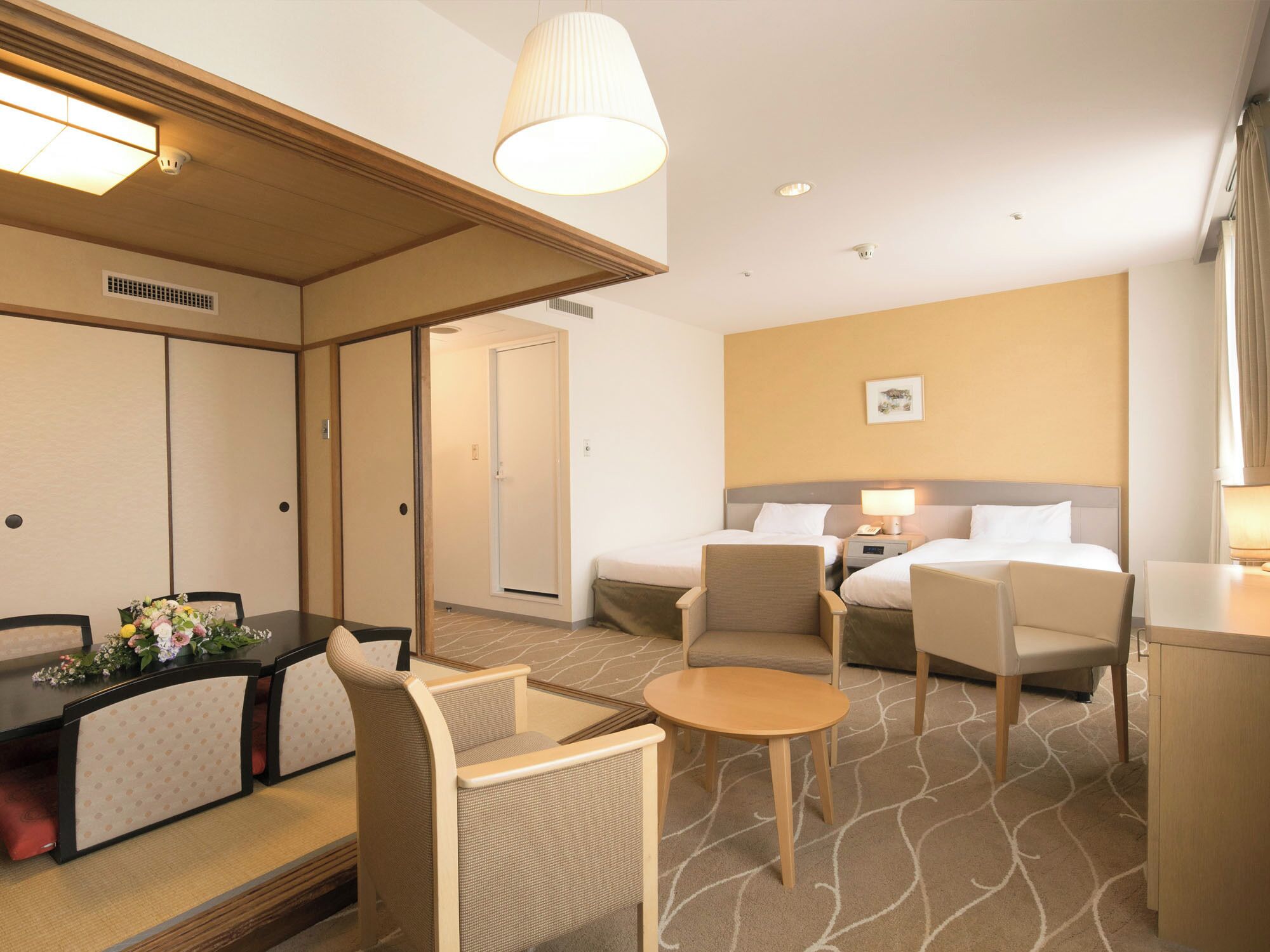 A hotel room with a dining area, two beds, a small table, and a sofa.