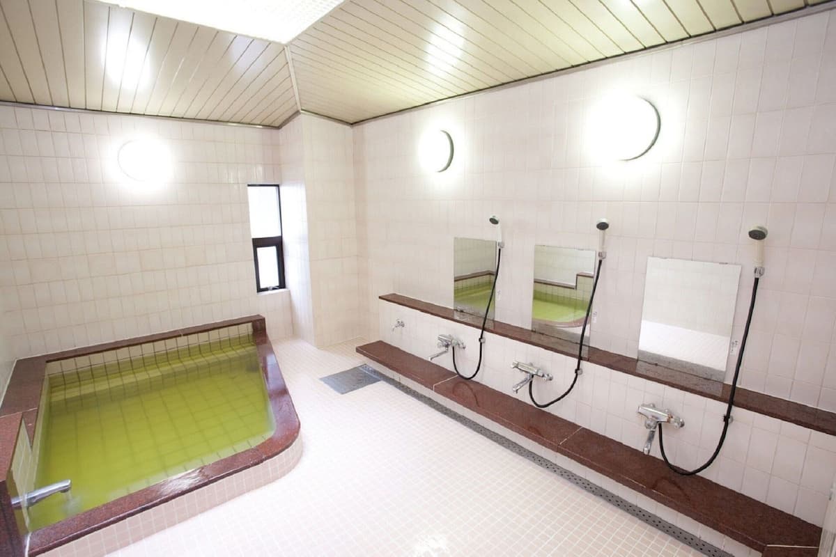 A public restroom with a large bathtub, multiple sinks, and mirrors.
