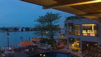 Relax by the rooftop pool surrounded by lounge chairs and umbrellas, with stunning views of the city and water.