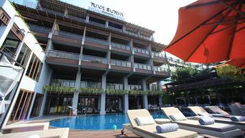 Un hotel con zona de piscina, varios balcones y sillones de descanso.