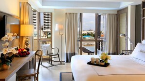 Habitación de hotel con cama, escritorio con lámpara, silla, ventana con cortinas y vistas al exterior.