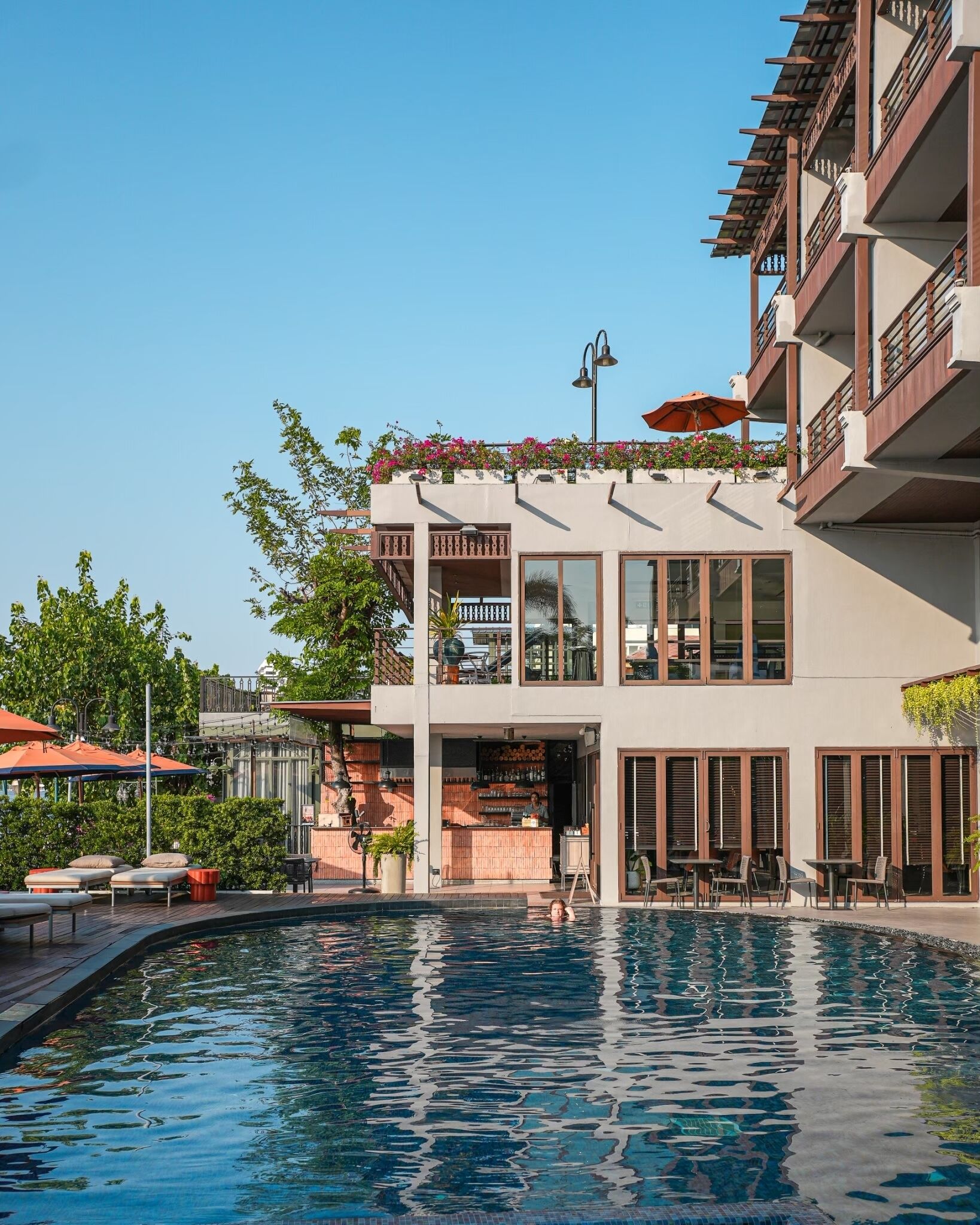 Un hotel moderno con piscina, zona de estar al aire libre y bar.