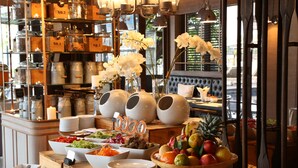 Montaje de bufé con diversos alimentos y elementos decorativos como orquídeas y jarrones.
