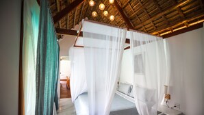 A bedroom with a canopy bed, a bedside table, and a nightstand.