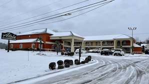 A hotel with a red facade, multiple parking spaces, and a snow-covered driveway.
