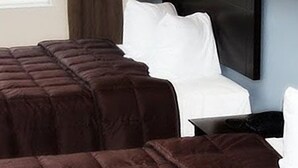 A hotel room with a large bed, a smaller bed, and a desk with a chair.