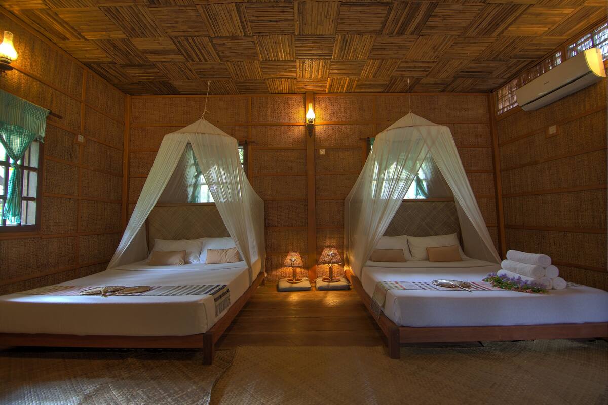 A room with two beds, each with a canopy, and a small table between them.