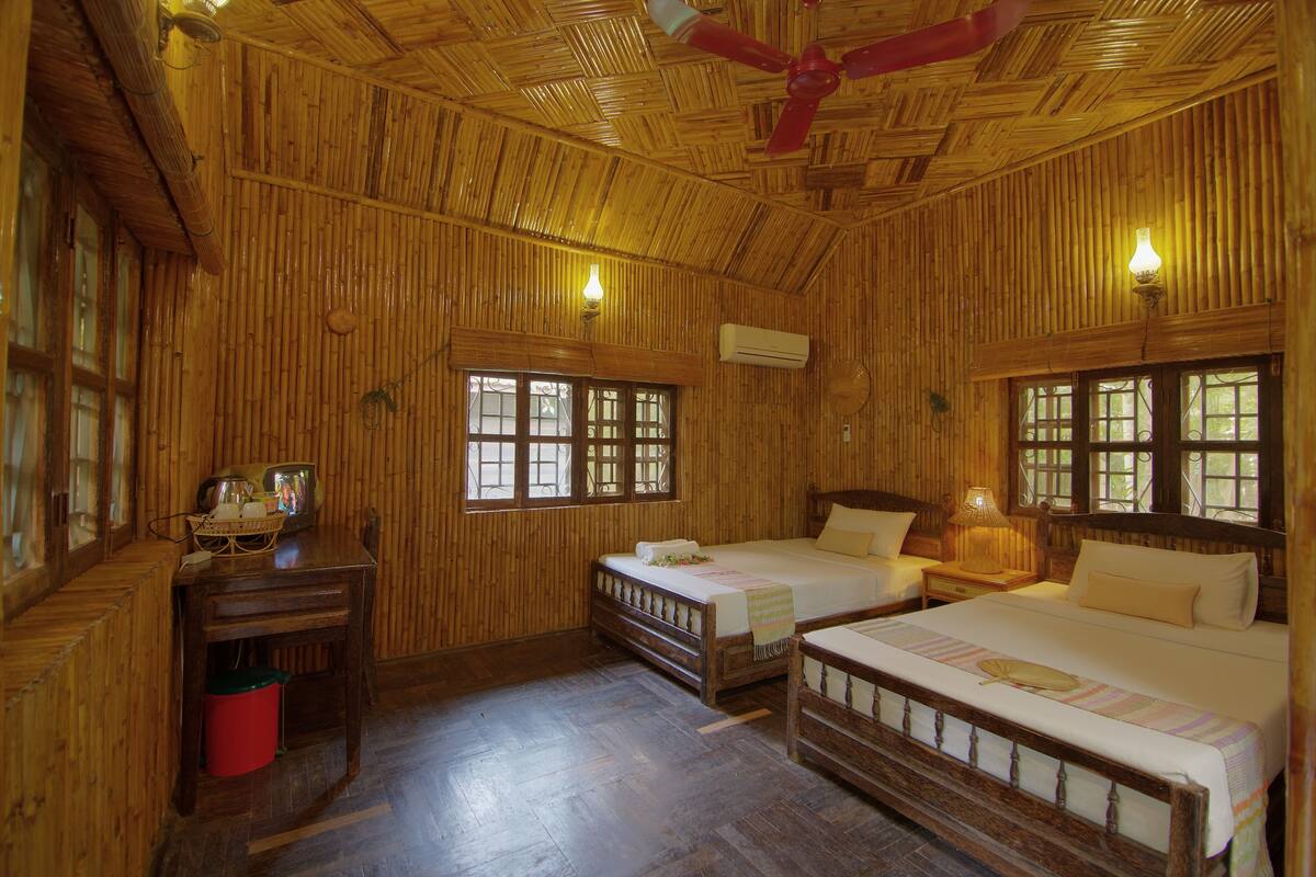 A room with two beds, a wooden ceiling, and a window.