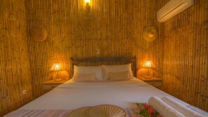 Een bed met hoofdbord, twee bedlampen en een decoratieve ventilator op een geruit kleed.