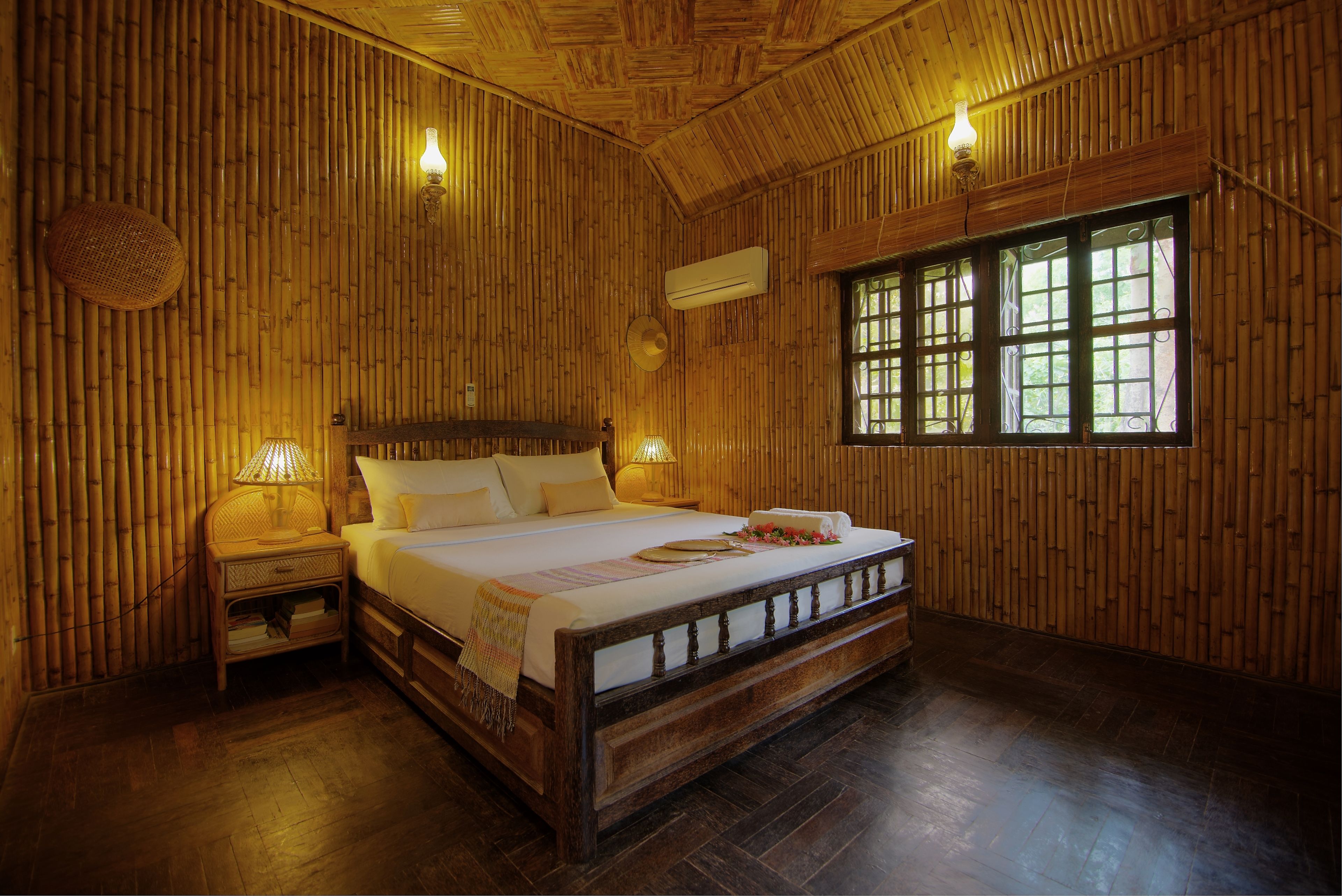 A wooden room with a bed, nightstands, and a window.