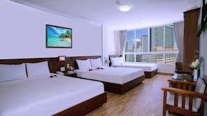 A hotel room with two beds, a wooden floor, a city view, and a painting on the wall. - Nice Swan Hotel (Nha Trang)