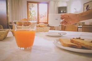 A breakfast setting with a glass of orange juice, croissants, and toast on a table. - Hotel Villa Marina (La Maddalena)