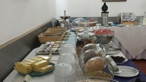 Una mesa de buffet con diversos alimentos, incluyendo pan, pasteles y salsas.