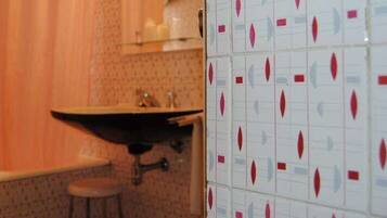 Un baño con lavamanos, inodoro y zona de ducha.