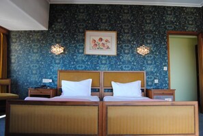 A double bed with a wooden headboard and two nightstands, a framed floral artwork above the bed, and a patterned wallpaper. - Hotel Miradouro (Porto)