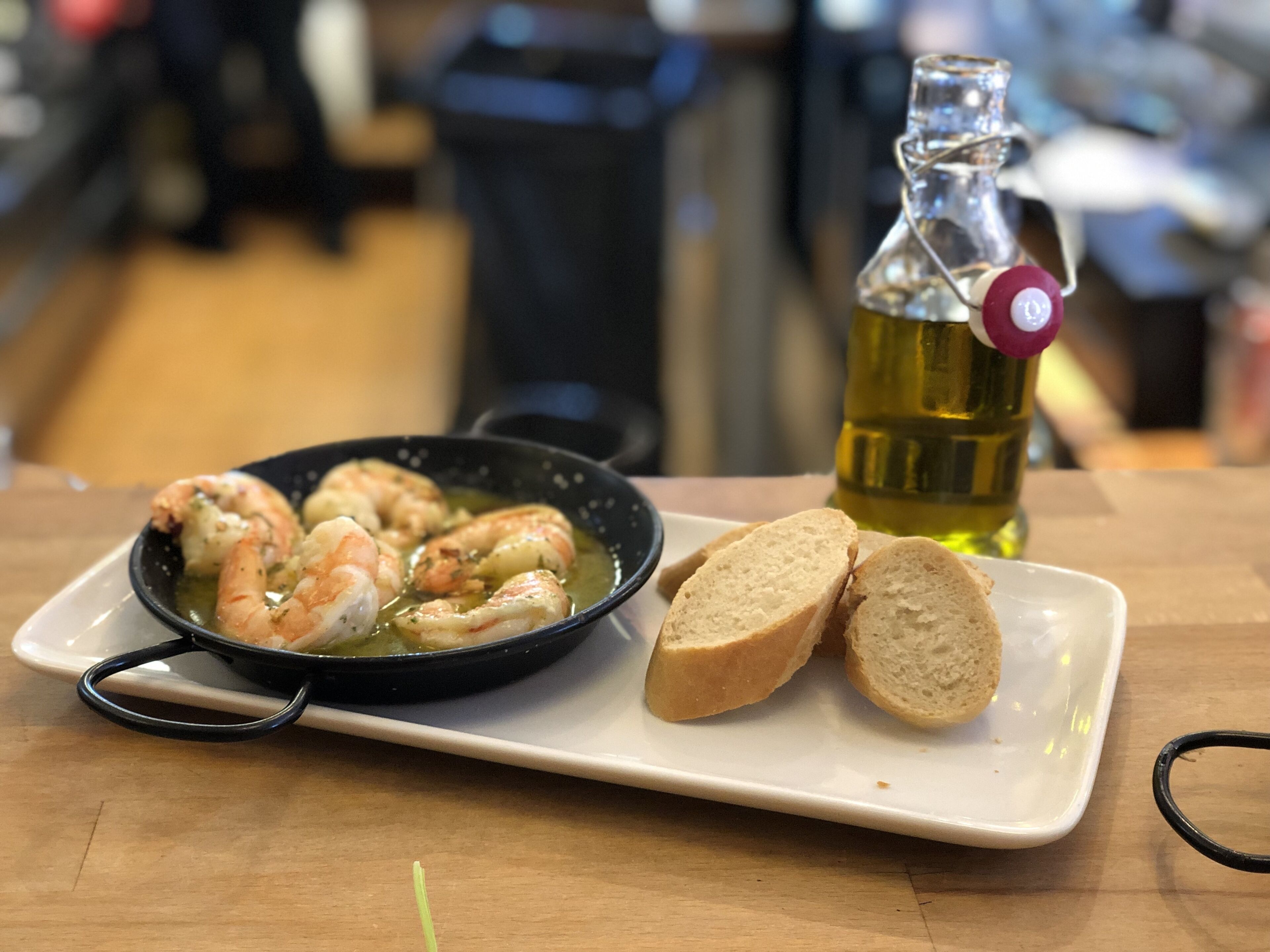Un plato con camarones cocidos y pan sobre una mesa.