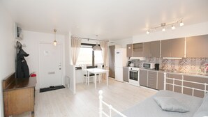 Una habitación de hotel moderna con una cama, un escritorio, una mesa de comedor y una kitchenette.