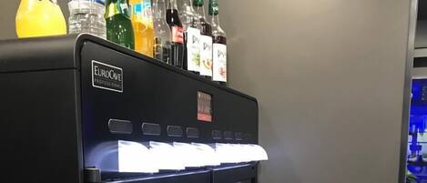 Un minibar con una variedad de bebidas en botella y un refrigerador de vino con copas vacías.