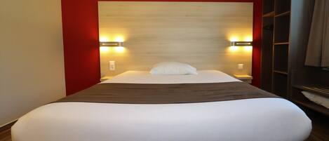 Habitación de hotel con una cama grande, dos lámparas de noche y un cabecero de madera.